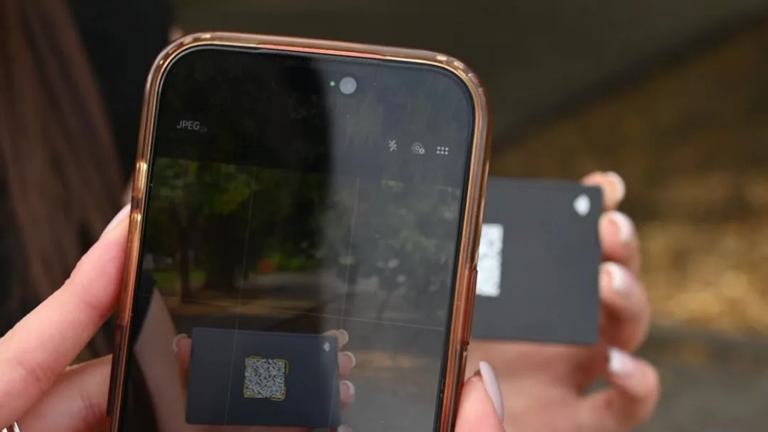 A phone camera scanning the QR code on a black Mibio metal card